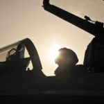 Piloto de combate con reloj IWC Top Gun en cabina al atardecer: Relojes de Aviador IWC