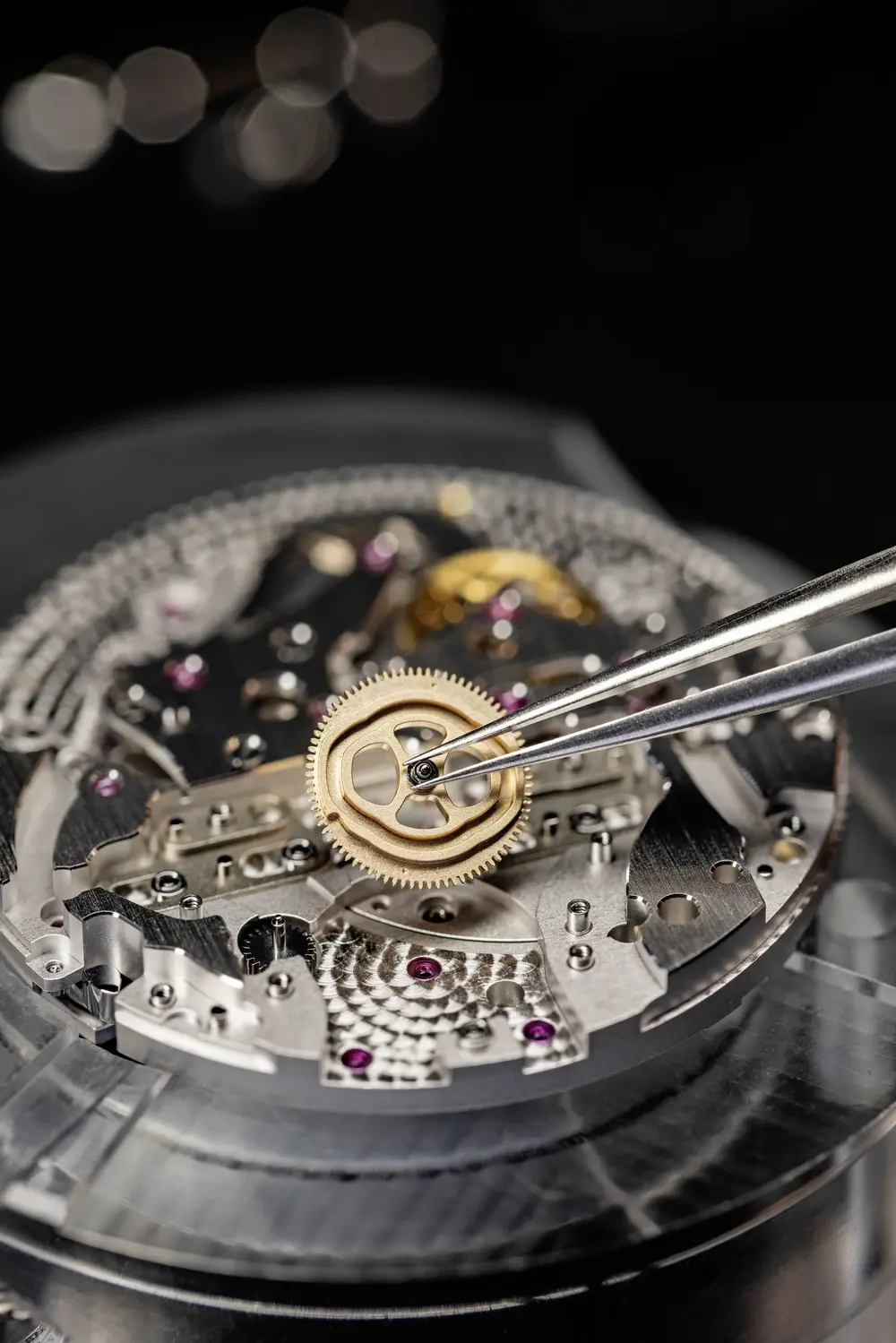 Artesanía en alta relojería detalle de fabricación con pinzas de relojero y rueda dentada micromecánica