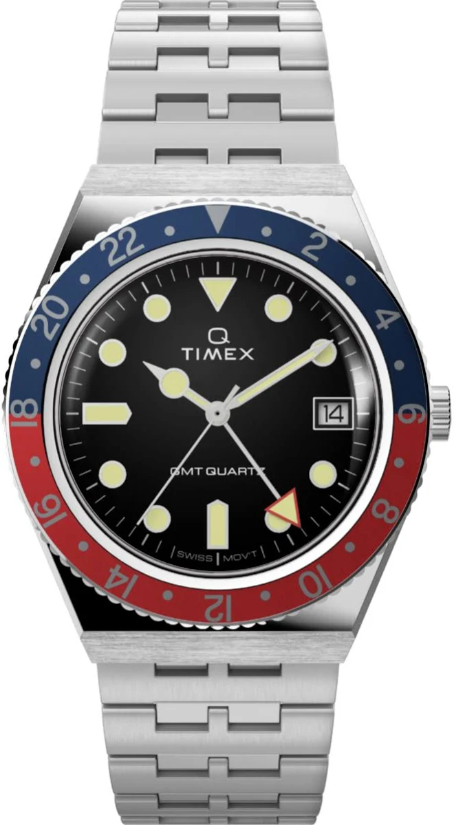 Q Timex con bisel bicolor rojo y azul estilo Pepsi, brazalete de acero tejido y esfera plateada con índices luminosos, representando el diseño retro de los años setenta