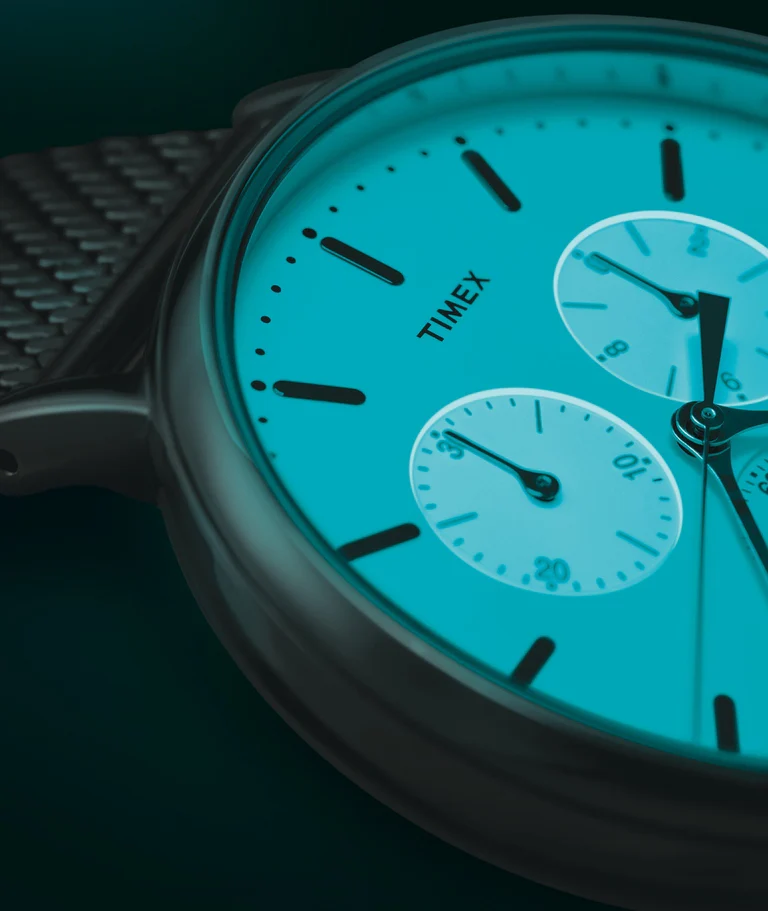 Esfera de reloj Timex iluminada con tecnología Indiglo, mostrando la característica retroiluminación turquesa uniforme que cubre toda la superficie del dial