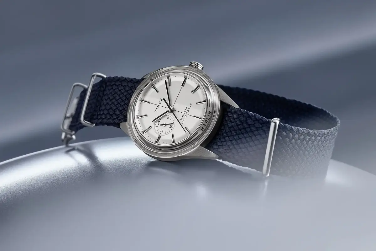 Timex Marlin Automatic sobre superficie oscura, mostrando su esfera sunburst y cristal acrílico abombado característico de los años sesenta